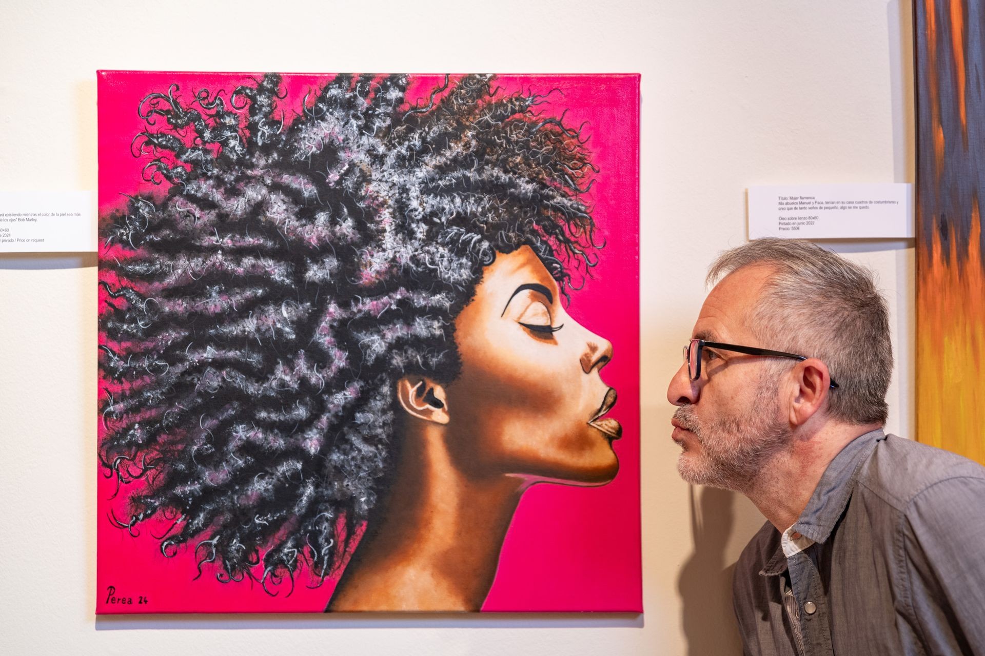 Man playfully interacts with colorful portrait of a woman on a gallery wall.